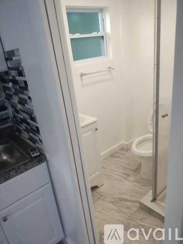 A bathroom with a toilet, sink, and a window.