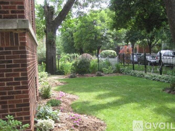 A garden with a brick wall on the left and a black fence on the right.