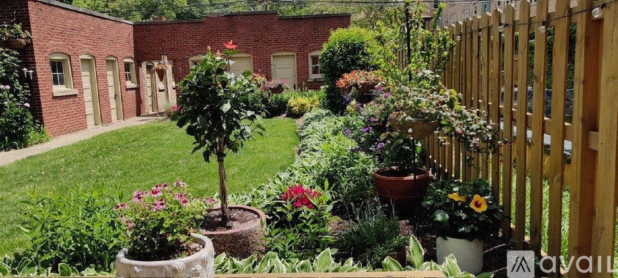 A garden with a wooden fence and a variety of plants and flowers.
