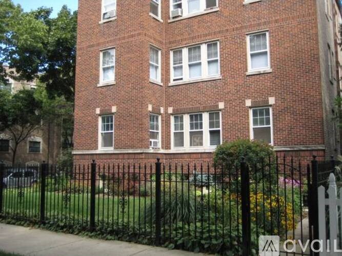 A red brick building with a black fence in front.