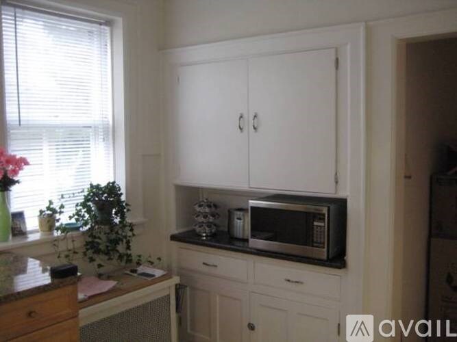 A kitchen with white cabinets and a microwave on top of the counter.