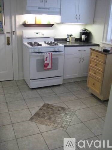 A kitchen with a white stove and white cabinets.