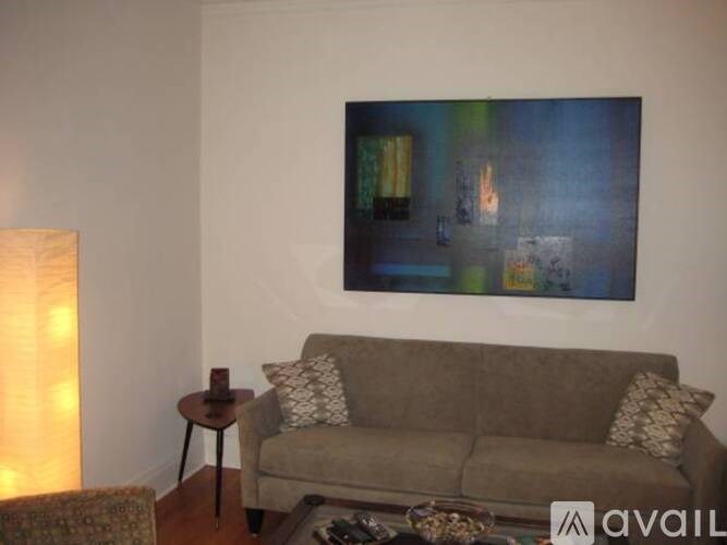 A living room with a couch, a table, and a painting on the wall.