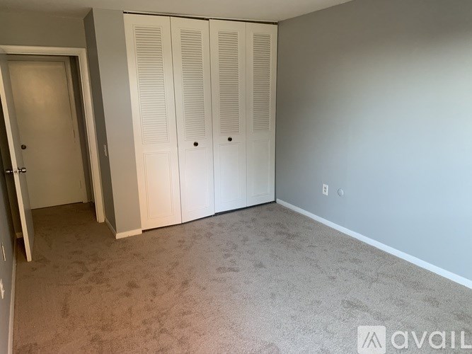 A room with white closet doors and a carpeted floor.