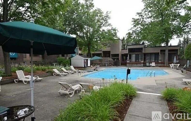 A pool surrounded by chairs and trees.