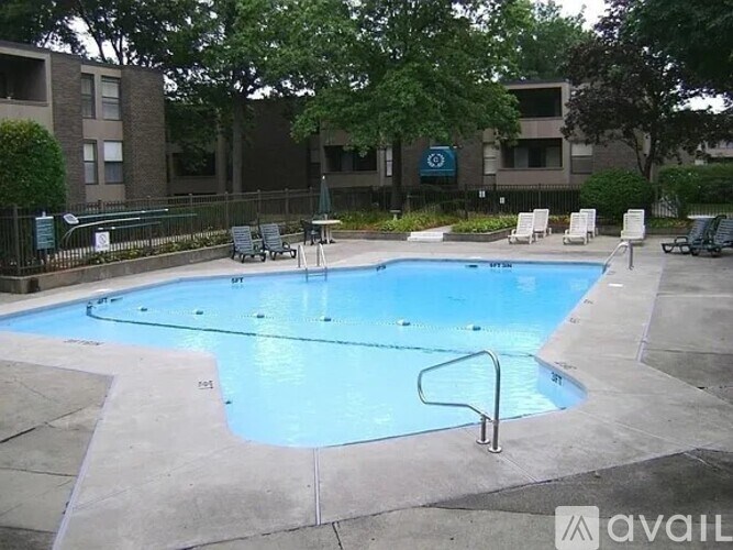 A large outdoor swimming pool surrounded by a concrete patio and lounge chairs.