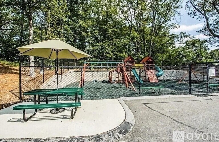 A playground with a green bench and a yellow umbrella.
