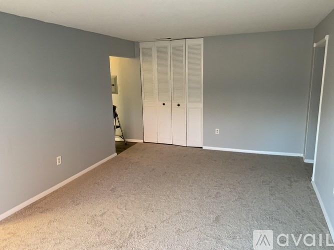 A room with grey walls and a carpeted floor with a white door and a white cabinet.