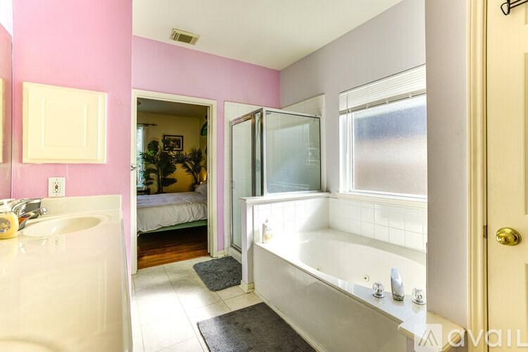 A bathroom with a pink wall and a white bathtub.