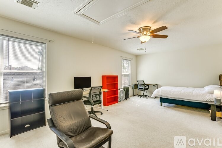 A room with a bed, chair, and ceiling fan.