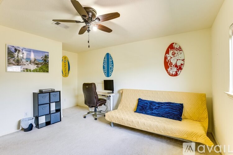 A room with a yellow couch and a ceiling fan.
