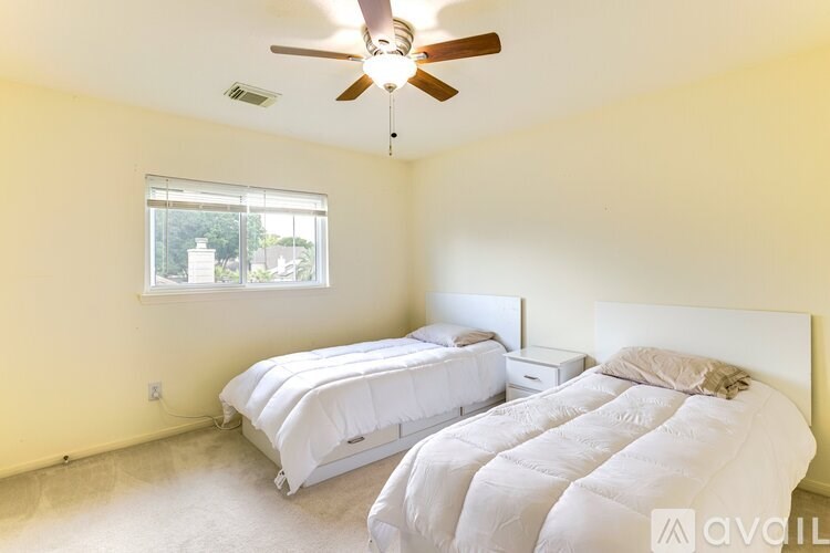 A bedroom with two beds and a ceiling fan.