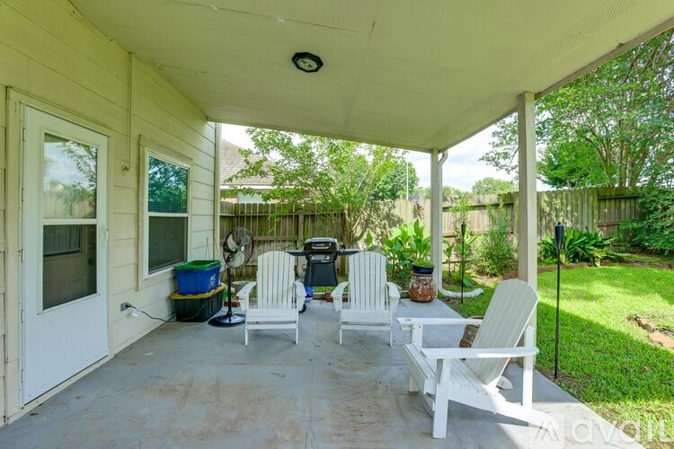 A patio with white furniture and a ceiling fan.