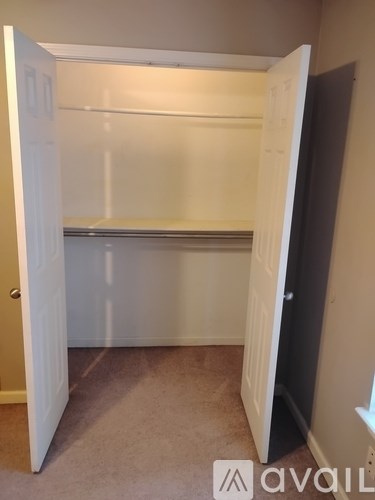 A white closet with a shelf and a door open.