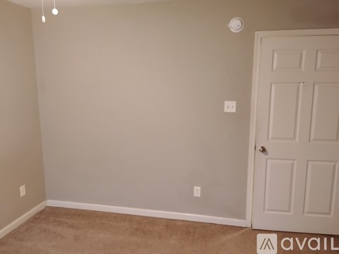 A room with a white door and a carpeted floor.