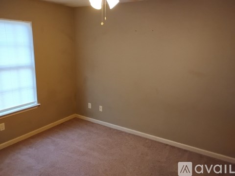 A room with a window and a carpeted floor.