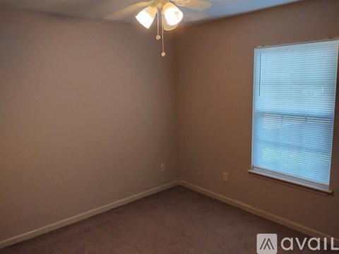 A room with a ceiling fan and a window with blinds.