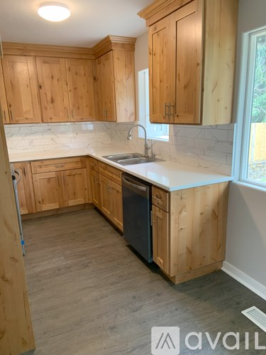 A kitchen with wooden cabinets and a black dishwasher.