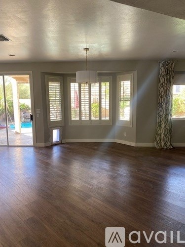 A room with wooden floors and a large window with blinds.