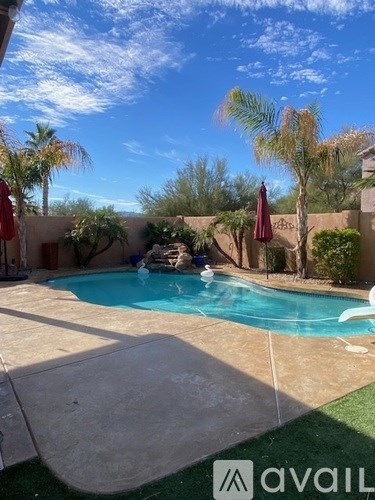 A pool surrounded by palm trees and a red umbrella.
