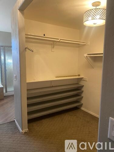 A room with a white wall and a grey carpet.