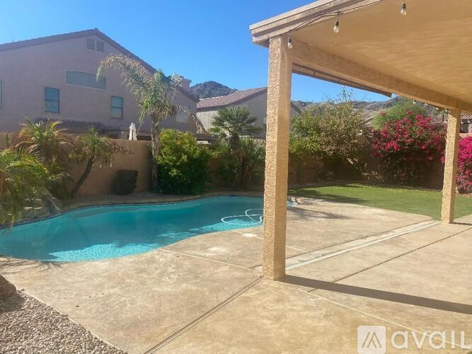 A pool in a backyard with a house and trees in the background.
