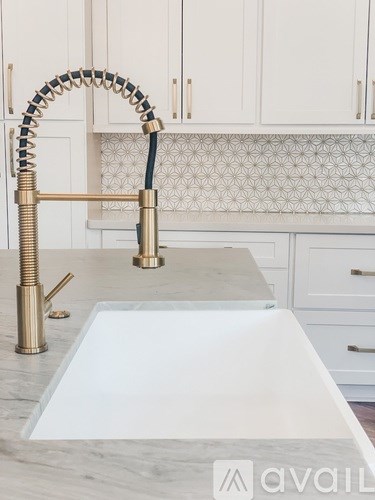 A kitchen sink with a gold faucet and a white countertop.