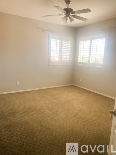 A room with a carpeted floor and a ceiling fan.