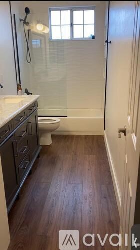 A bathroom with wood floors and white walls.