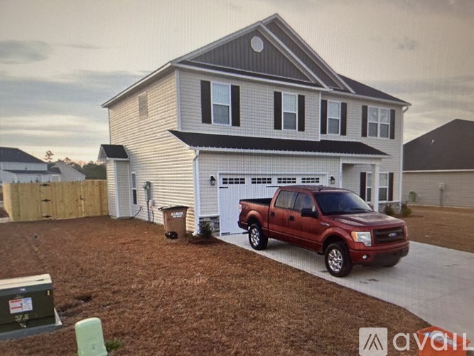 A red pickup truck is parked in front of a two-story house.