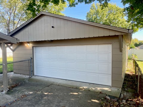 A garage with a white door is attached to a house.