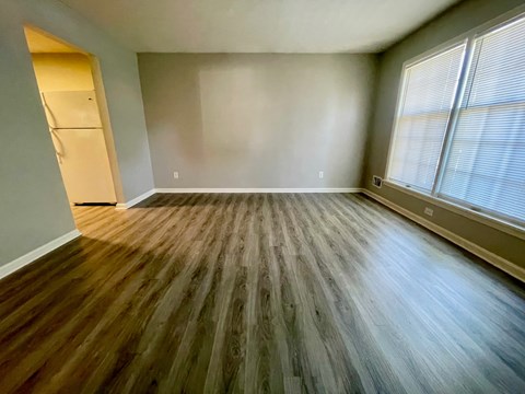 A room with wooden flooring and a window on the right side.