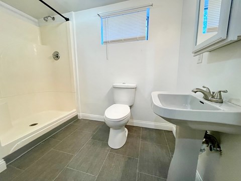 A white toilet sits in a bathroom next to a sink.