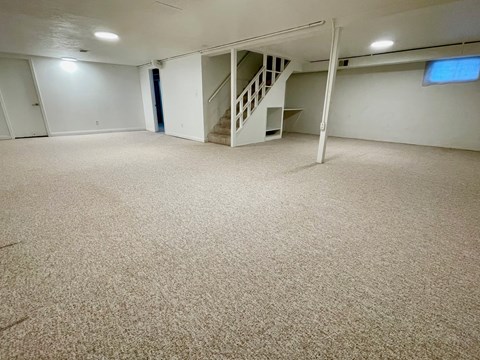 A room with a carpeted floor and a staircase.