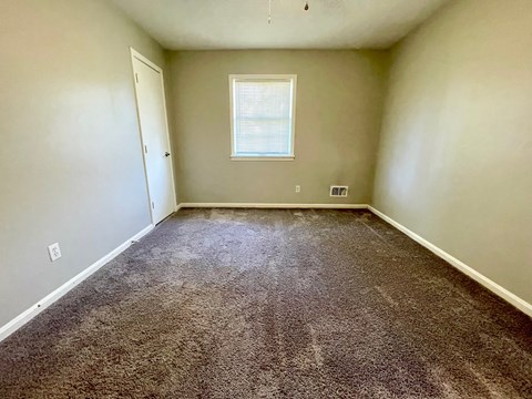 A room with a carpeted floor and a window.
