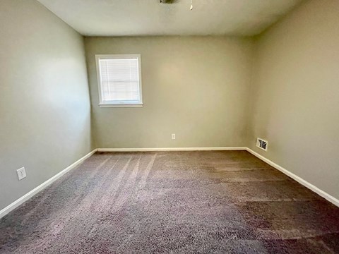 A room with a carpeted floor and a window.