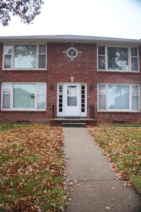 A brick house with a white door and windows.