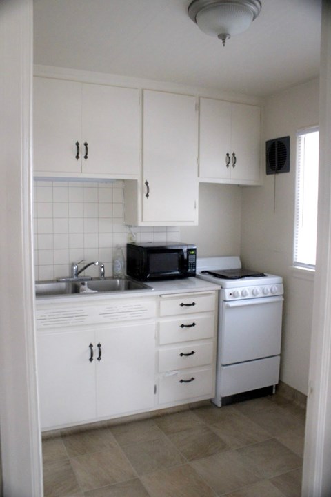 A white kitchen with a microwave, oven, and sink.