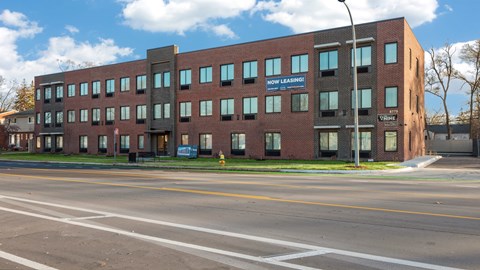 A building with a sign that says "NOW LEASING" on the side of it.