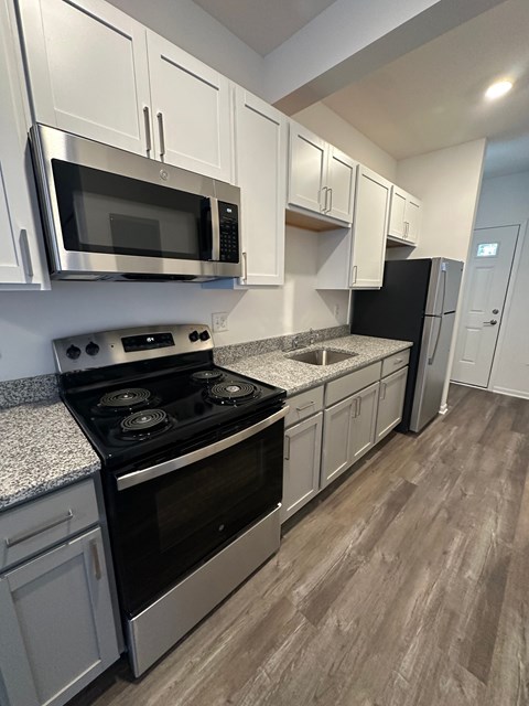 A kitchen with a stove, microwave, and refrigerator.