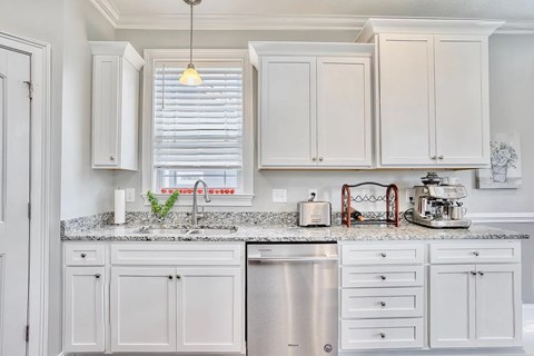 A kitchen with white cabinets and a granite countertop.