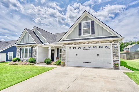 A two-car garage is attached to a house with a blue and white exterior.