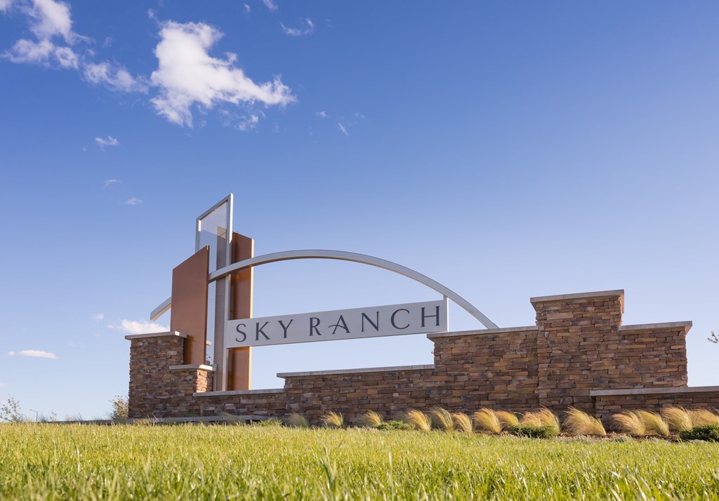 A sign that says "Sky Ranch" is mounted on a stone wall.