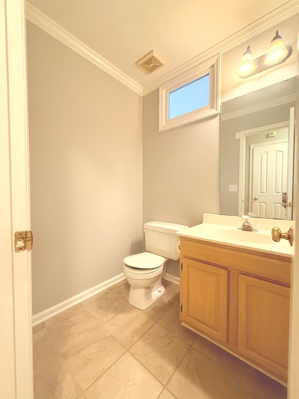 A bathroom with a toilet, sink, and mirror.