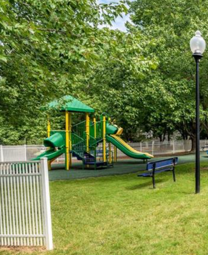 A playground with a green slide and a yellow canopy.