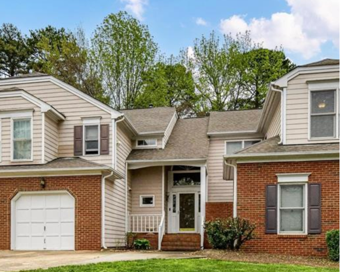 A house with a white garage door and a brick wall.