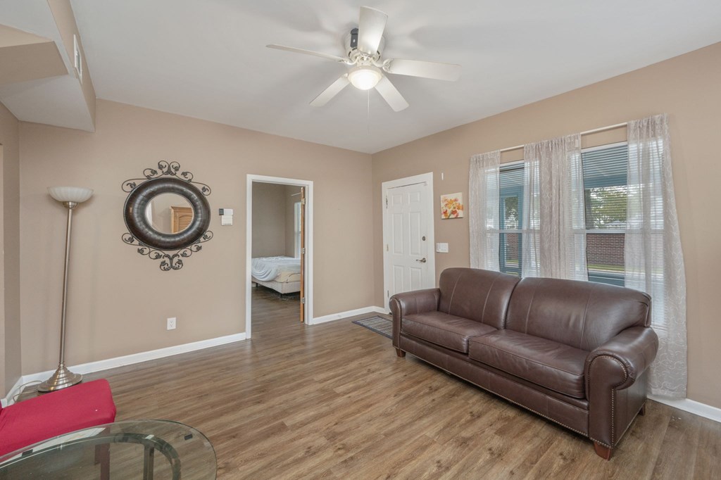 A living room with a brown leather couch and a glass coffee table.