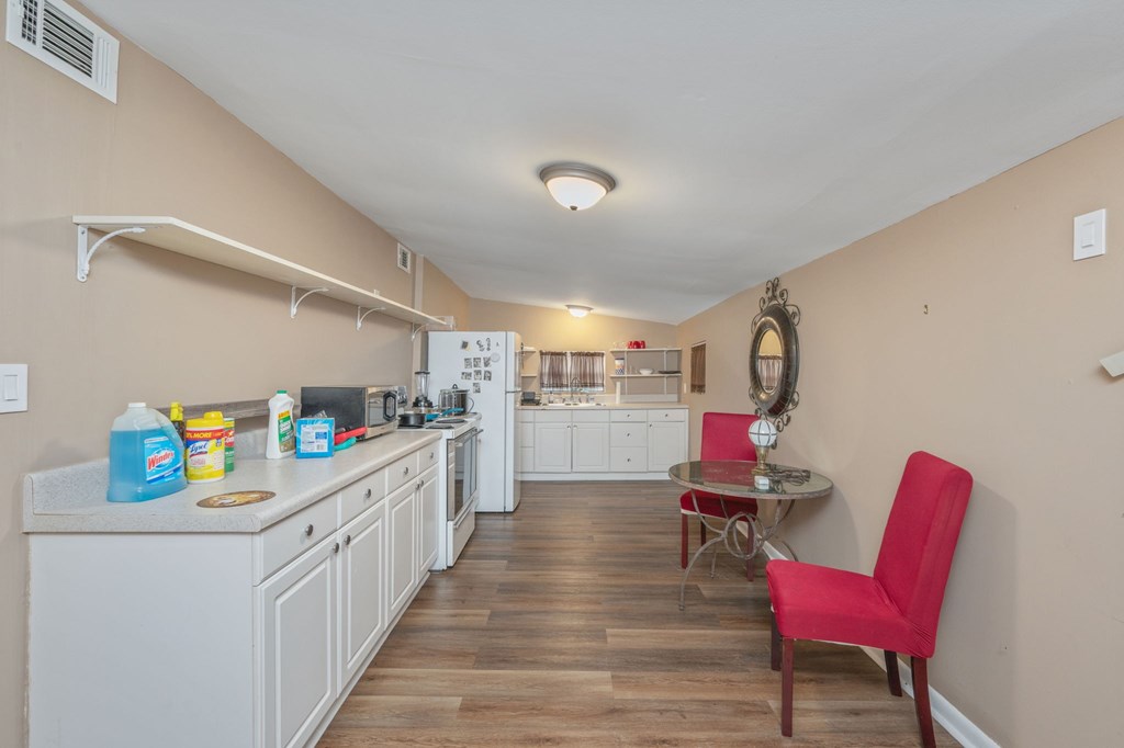 A kitchen with a red chair and a table with a mirror on the wall.