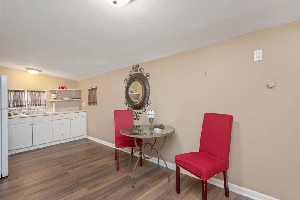 A red chair sits in a room with a round mirror and a small table.