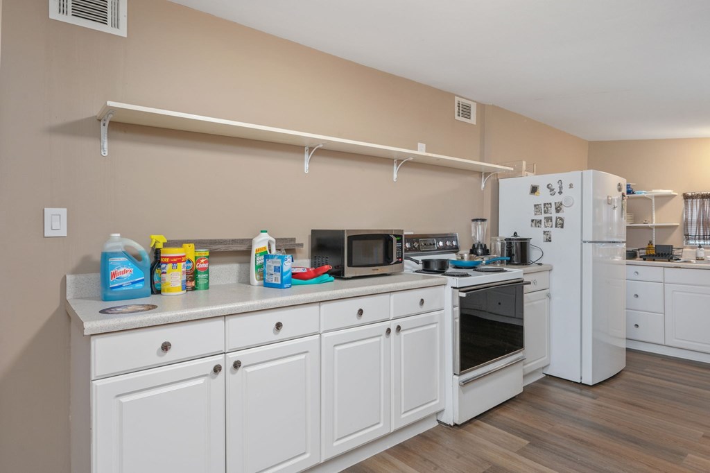 A kitchen with white cabinets and a wooden floor.